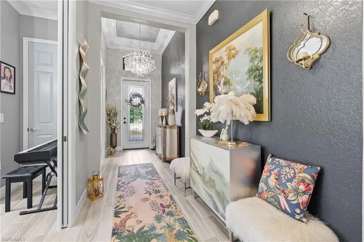 Home office featuring built in shelves, crown molding, a chandelier, and wood finish floors