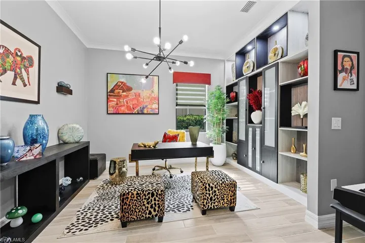 Home office featuring built in shelves, crown molding, a chandelier, and wood finish floors