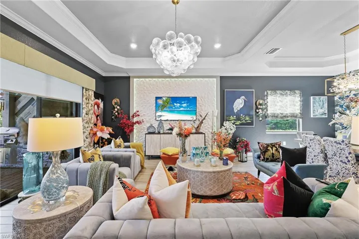 Living room with a chandelier, ornamental molding, recessed lighting, tile finished floors, and a raised ceiling