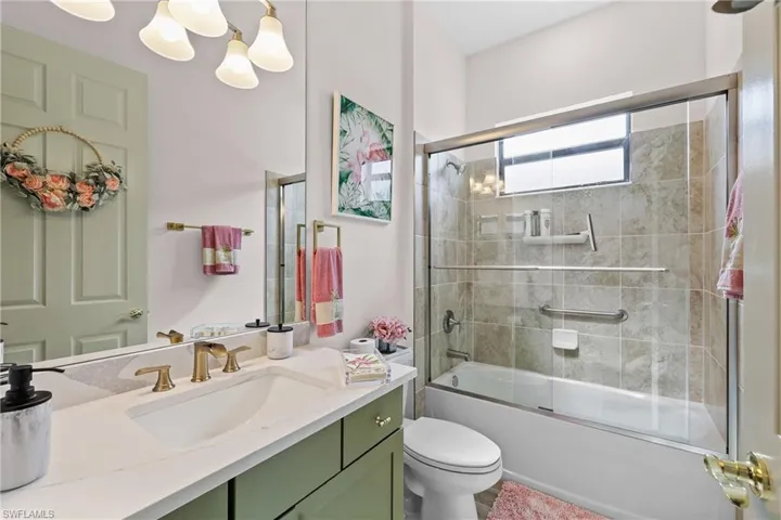 Full bath with vanity, enclosed tub / shower combo, and a chandelier