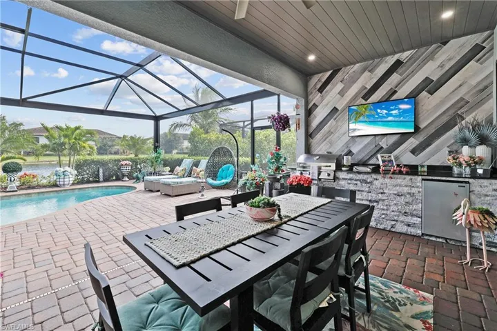 View of patio featuring a sunroom, glass enclosure, outdoor dining space, area for grilling, and an outdoor pool