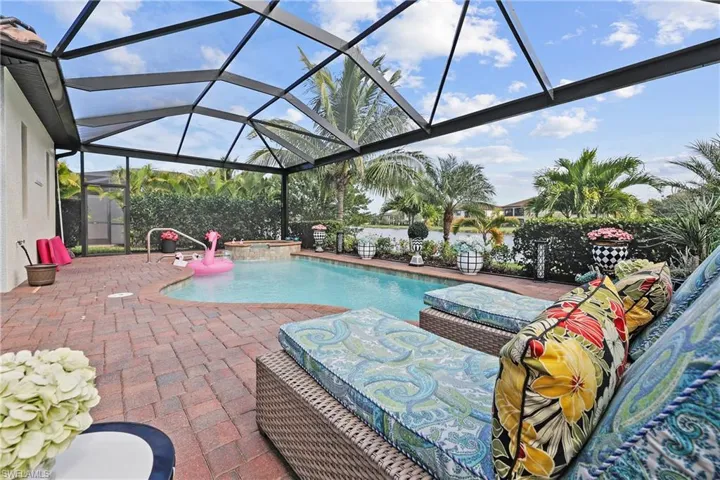 View of pool featuring screen enclosure, a patio area, a sunroom, and a pool with connected hot tub