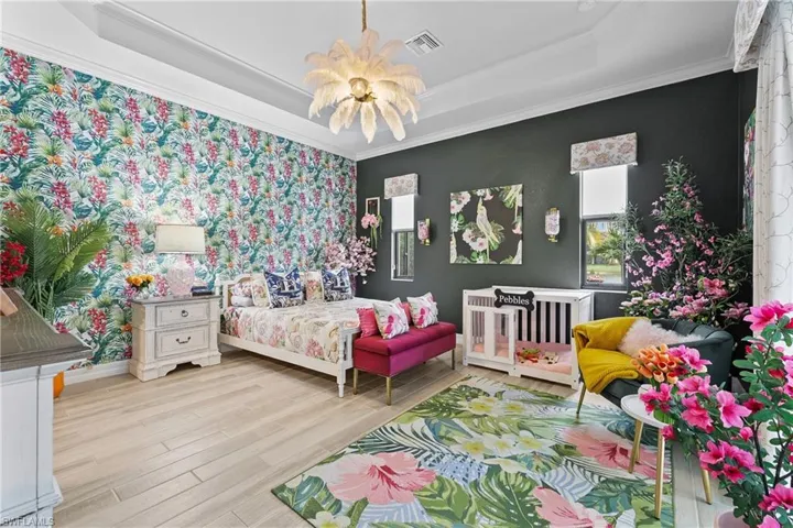 Bedroom with a chandelier, an accent wall, tile finished floors, and a raised ceiling