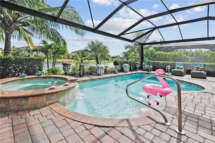 View of swimming pool featuring a pool with connected hot tub, glass enclosure, a patio, and a sunroom