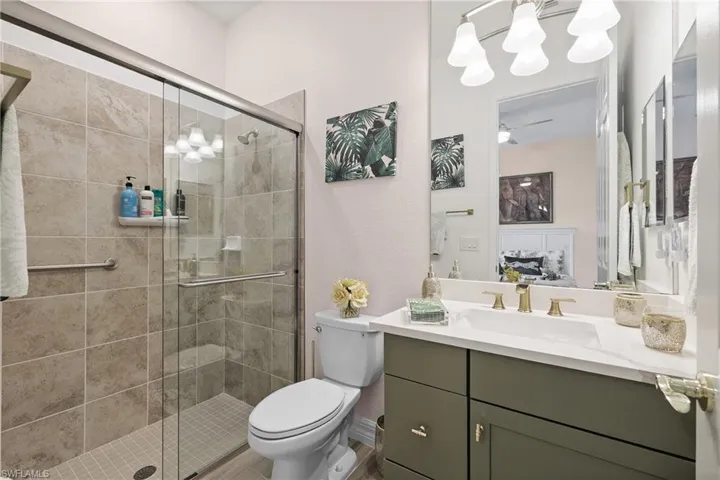 Ensuite bathroom featuring vanity, a stall shower, a chandelier, and a textured wall