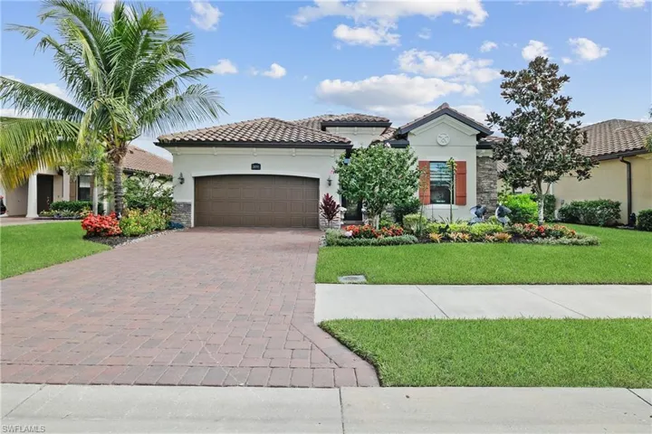 Mediterranean / Spanish house with stone siding, a front yard, stucco siding, and decorative driveway