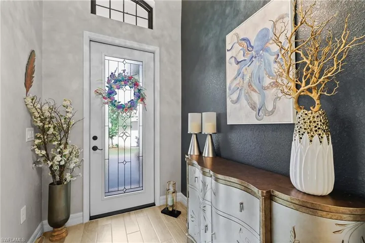 Foyer entrance with light plank tile-style floors and a textured wall