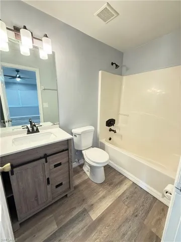Bathroom with vanity,  shower combination, laminate  flooring, and a ceiling fan