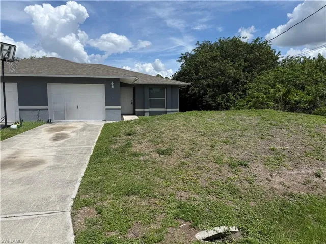 View of front of home featuring a front lawn, an attached garage, driveway, roof with shingles, and stucco siding