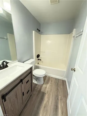 Bathroom with vanity, laminate flooring, and shower / washtub combination
