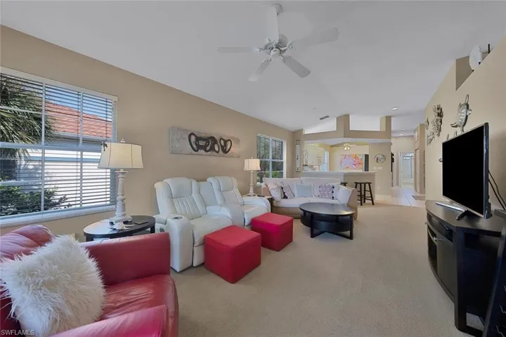 Carpeted living room featuring ceiling fan and lofted ceiling