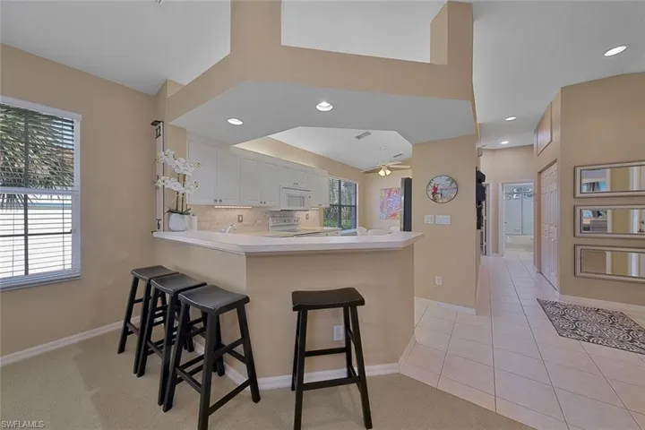 Kitchen with white cabinetry, white appliances, tasteful backsplash, ceiling fan, and kitchen peninsula