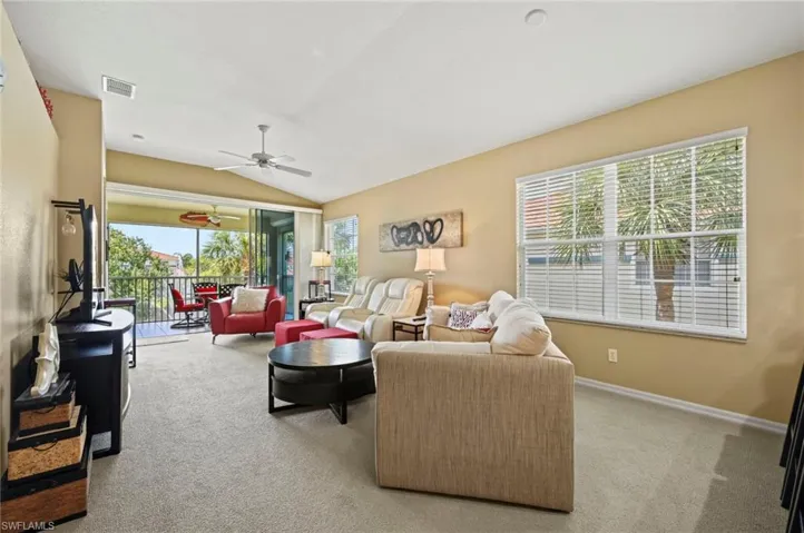 Living room featuring ceiling fan, plenty of natural light, light colored carpet, and lofted ceiling
