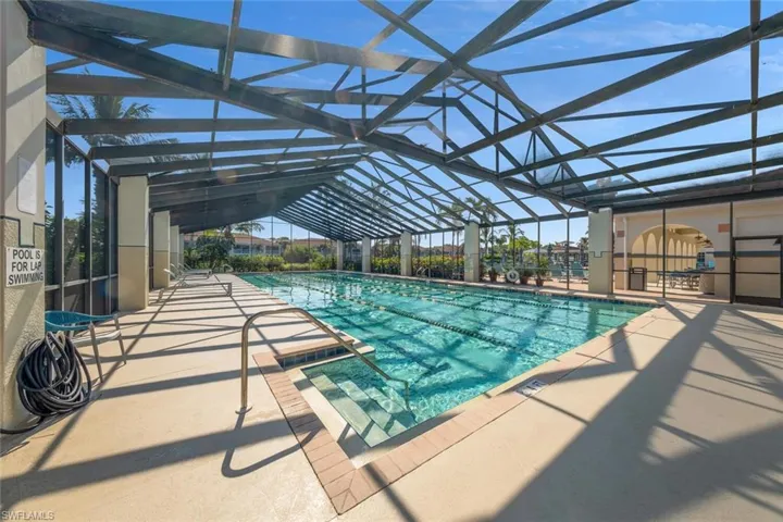 View of swimming pool with glass enclosure and a patio