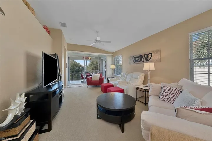 Living room with carpet, vaulted ceiling, and ceiling fan