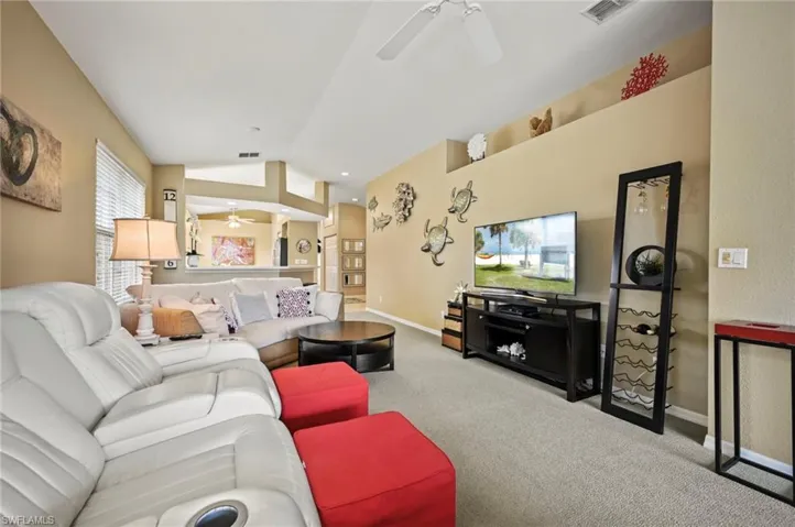 Carpeted living room featuring ceiling fan and lofted ceiling