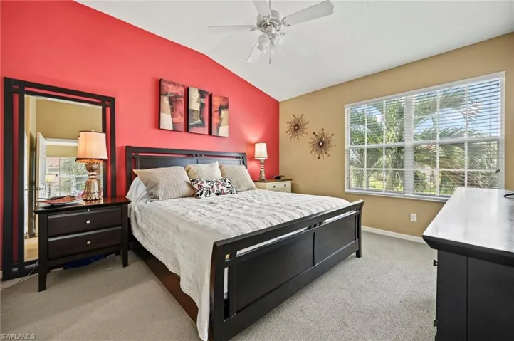 Carpeted bedroom with ceiling fan and vaulted ceiling