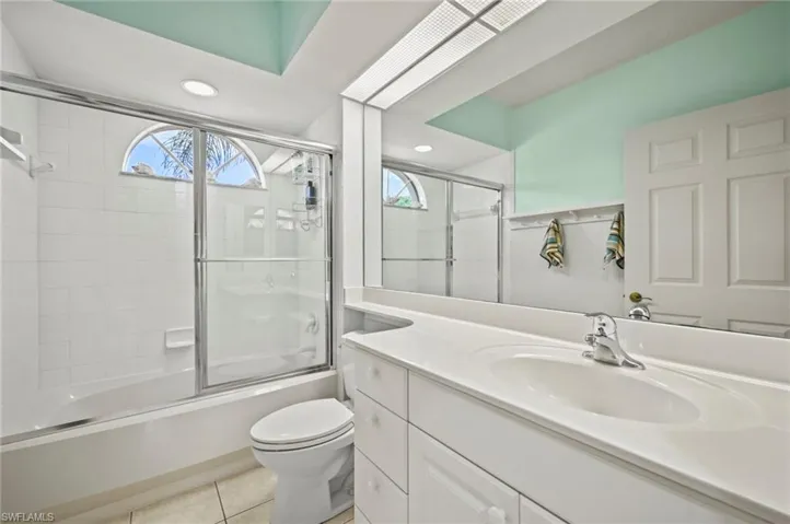 Full bathroom featuring tile patterned flooring, toilet, vanity, and bath / shower combo with glass door