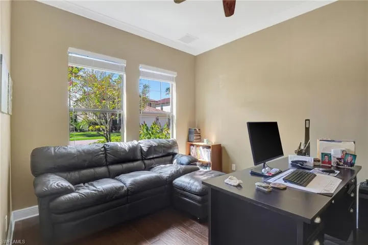 Office area with dark wood-style floors, ceiling fan, and ornamental molding