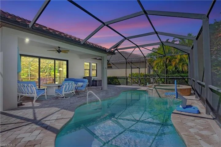 View of pool featuring a patio, a pool with connected hot tub, a ceiling fan, a lanai, and an outdoor living space