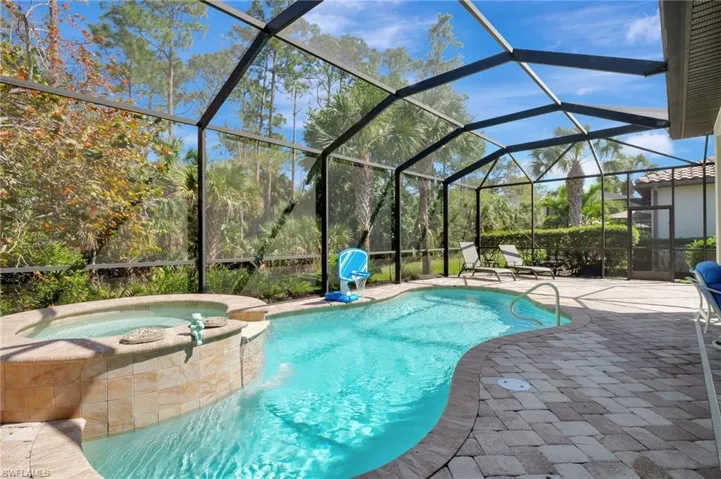 View of pool with glass enclosure, a patio area, and a pool with connected hot tub