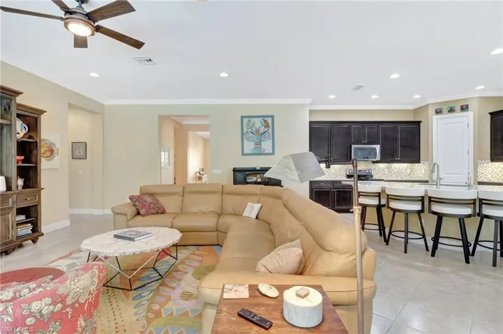 Living room with recessed lighting, light tile patterned flooring, crown molding, and visible vents
