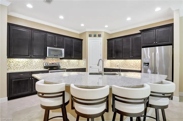Kitchen featuring stainless steel appliances, a breakfast bar, a sink, and a center island with sink