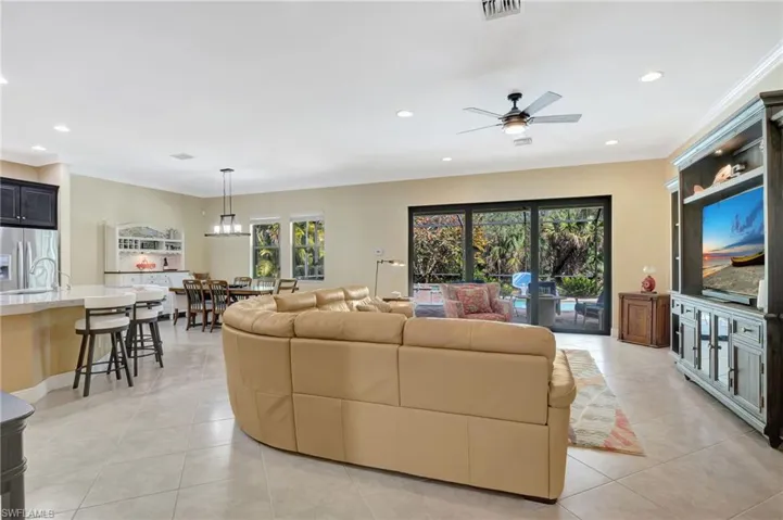 Living room with light tile patterned floors, recessed lighting, a ceiling fan, visible vents, and crown molding