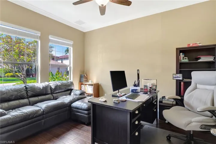 Office with dark wood-style floors, ceiling fan, and crown molding