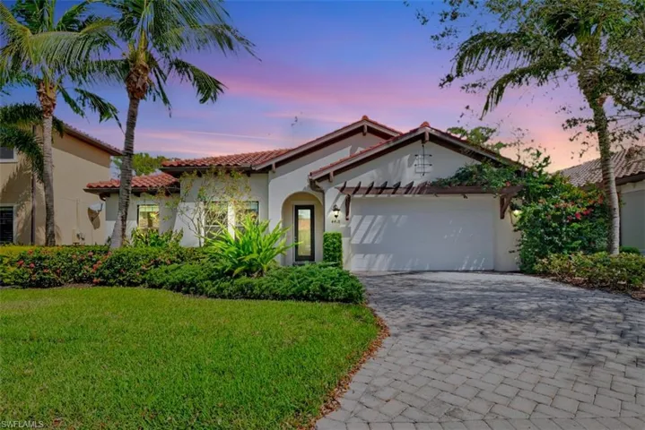 Mediterranean / spanish home with a front yard, decorative driveway, an attached garage, and stucco siding