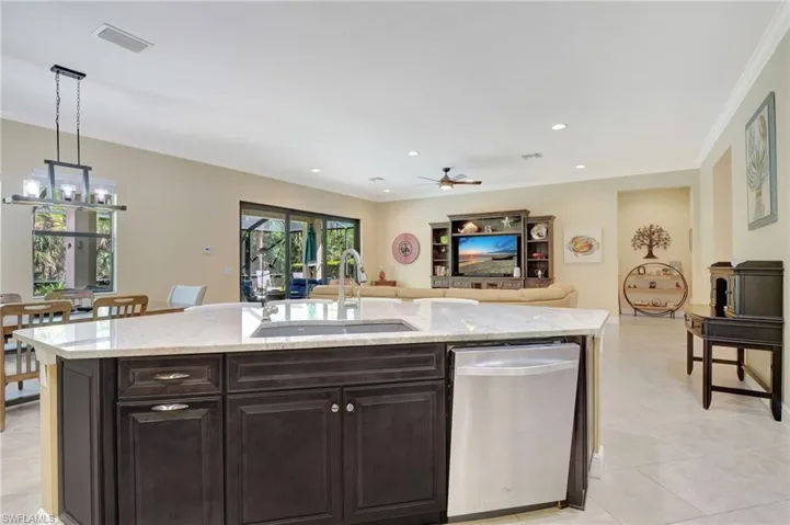 Kitchen with a center island with sink, hanging light fixtures, stainless steel dishwasher, open floor plan, and a sink