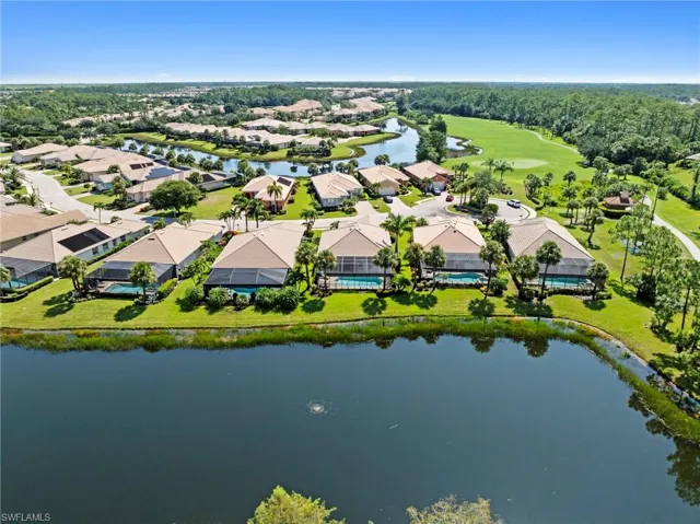 Waterfront community featuring elegant single-story residences with neutral-toned exteriors, manicured lawns, mature landscaping, and direct lakefront access along a serene water feature
