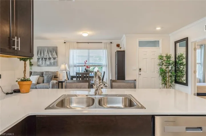 Kitchen with sink, dark brown cabinets, and ornamental molding