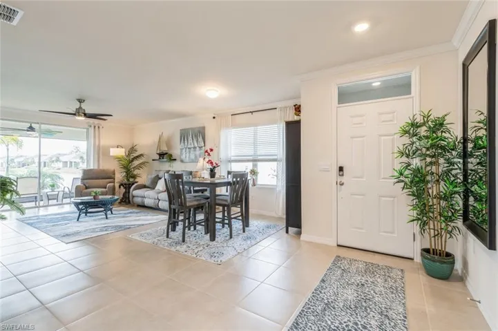 Tiled dining room with ornamental molding and ceiling fan