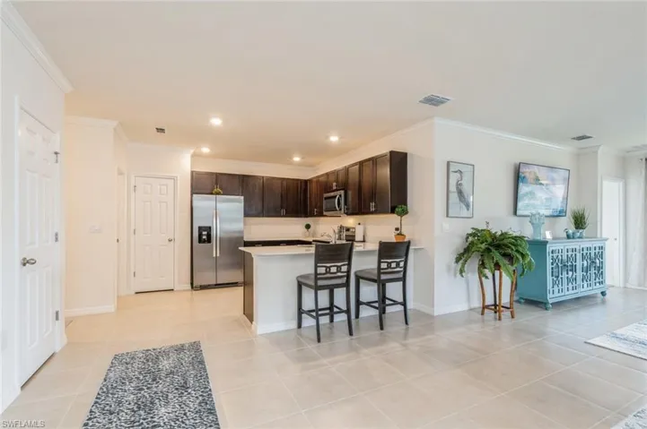 Kitchen featuring stainless steel appliances, dark brown cabinetry, kitchen peninsula, a kitchen bar, and light tile patterned floors