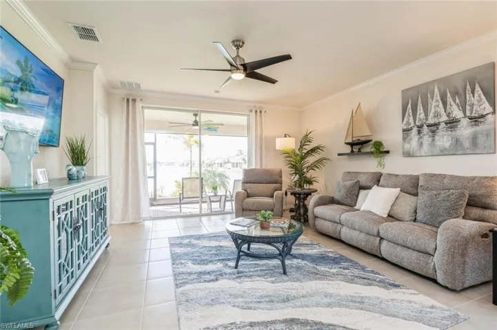 Tiled living room with ornamental molding and ceiling fan