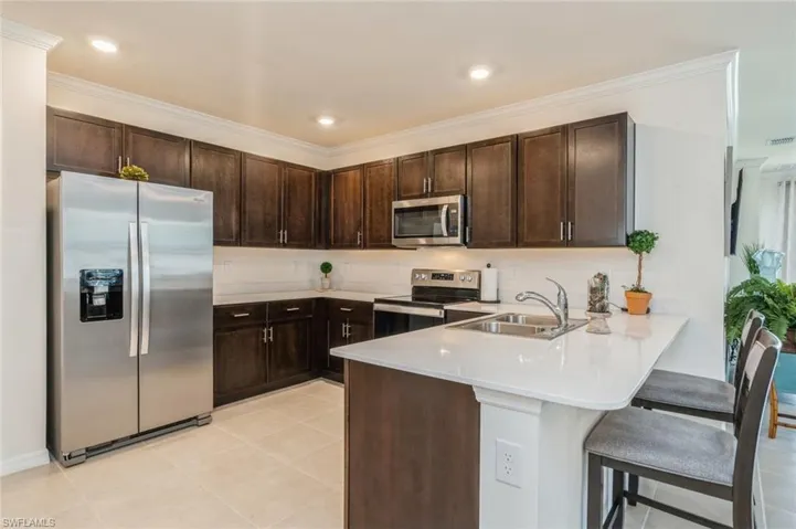 Kitchen with kitchen peninsula, sink, dark brown cabinetry, and stainless steel appliances