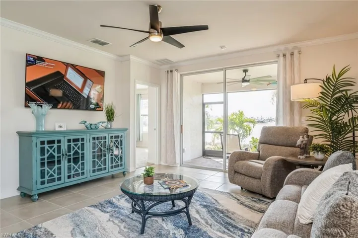 Living room featuring ornamental molding, light tile patterned floors, and ceiling fan