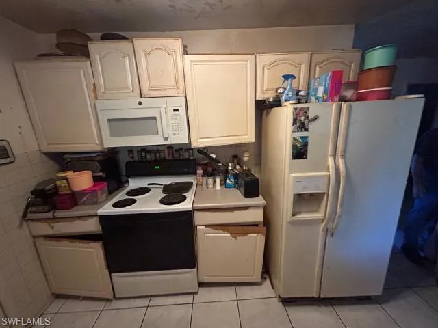 Kitchen featuring white cabinetry, white appliances, and light tile patterned floors