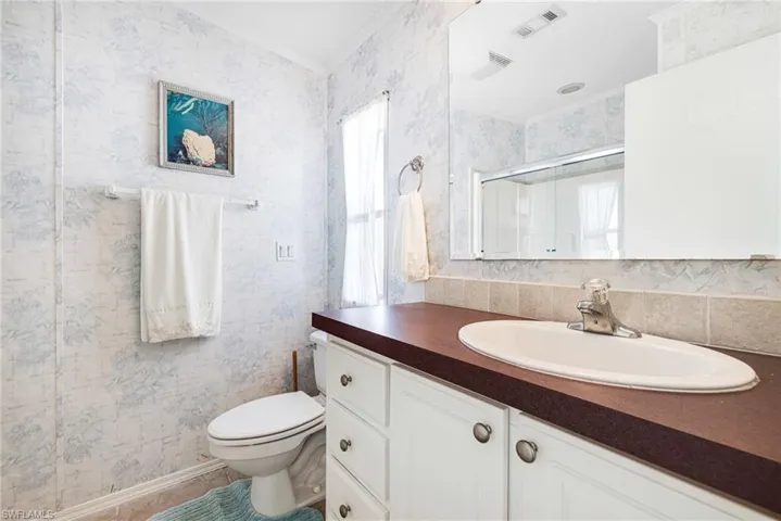 Bathroom featuring walk in shower, vanity, ornamental molding, and toilet