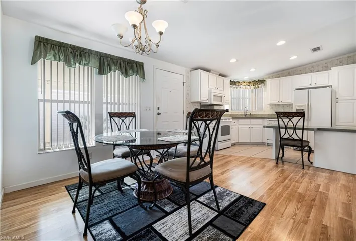 Dining area with light hardwood / wood-style flooring, a chandelier, vaulted ceiling, and sink