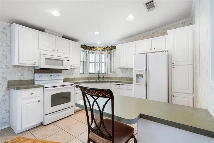 Kitchen with sink, light tile patterned floors, white appliances, white cabinets, and ornamental molding