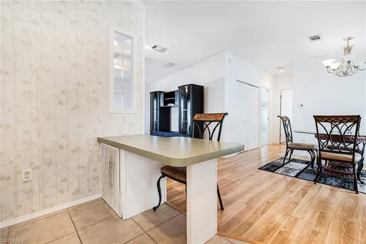 Kitchen with a kitchen bar, kitchen peninsula, light hardwood / wood-style flooring, a chandelier, and hanging light fixtures