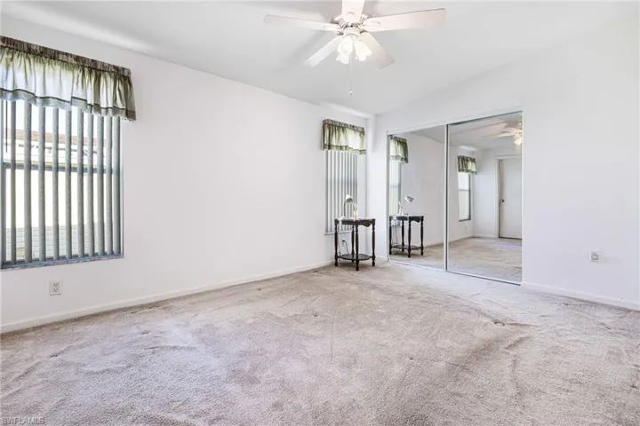 Carpeted spare room featuring ceiling fan, plenty of natural light, and lofted ceiling