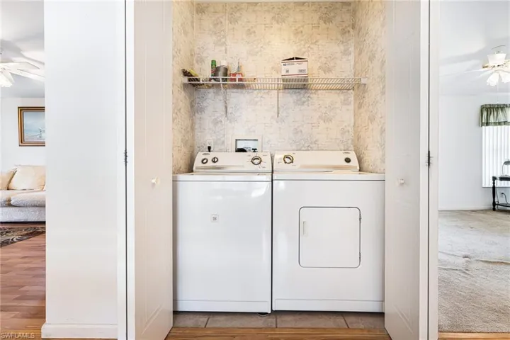 Clothes washing area with light hardwood / wood-style flooring, washer and clothes dryer, and ceiling fan