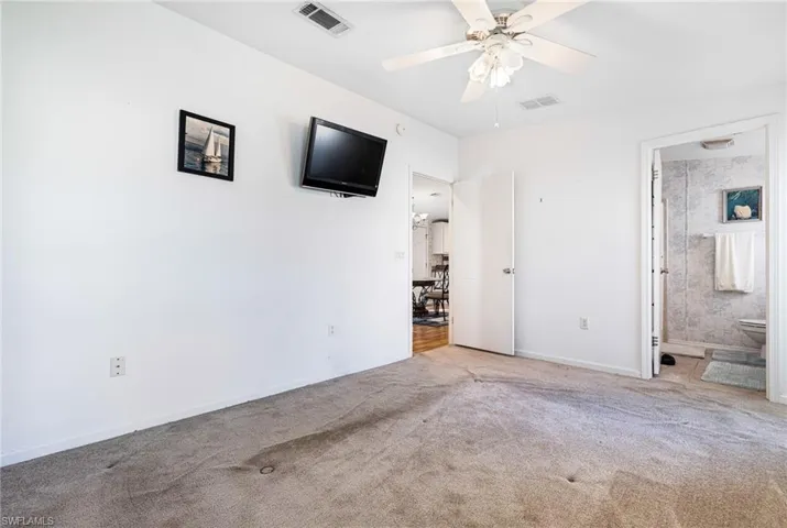 Unfurnished bedroom with ensuite bath, ceiling fan, and light colored carpet