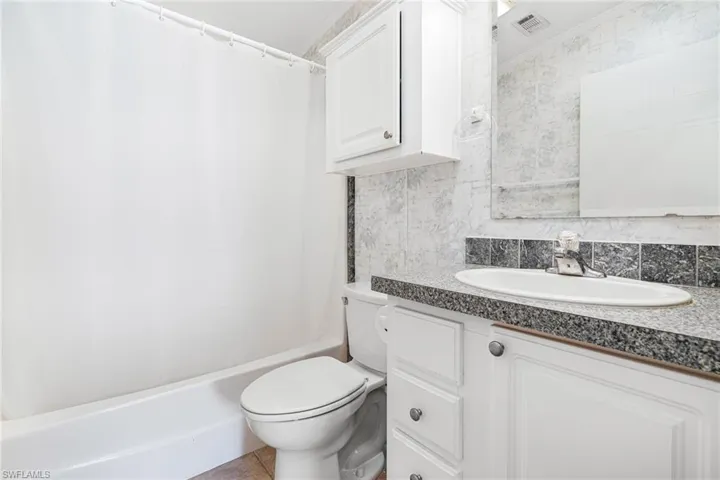 Full bathroom with tasteful backsplash, tile patterned floors, toilet, vanity, and ornamental molding