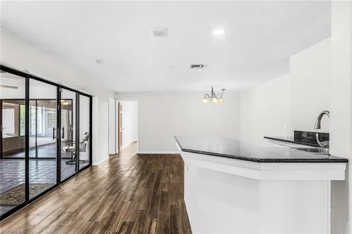large wet bar with granite, sink and refrigerator, and seating with view of pool