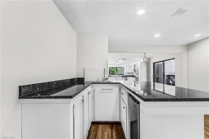 large wet bar with granite, sink and refrigerator, and seating with view of pool