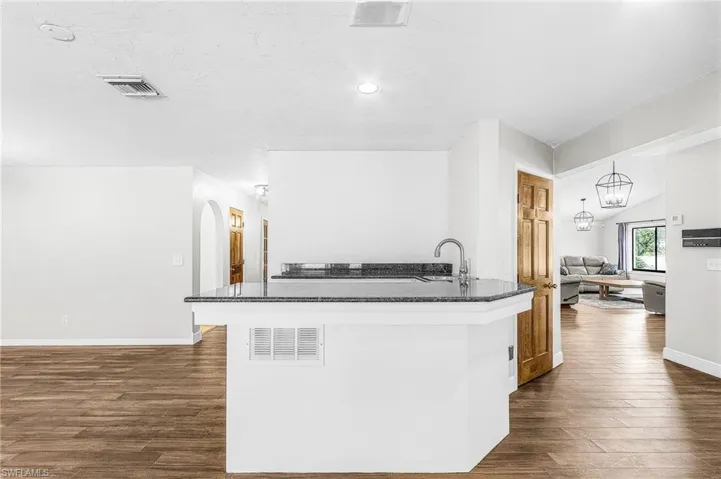 large wet bar with granite, sink and refrigerator, and seating with view of pool